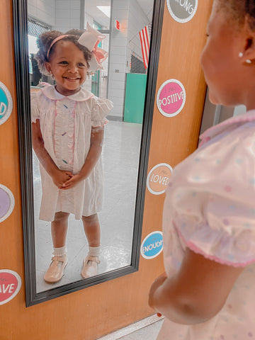 little girl looking in the mirror and her outfit with her Wee Ones hiar bow.