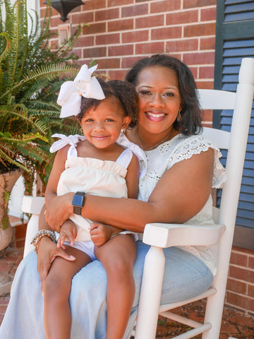 mother holding little girl wearing a  king size white hair bow