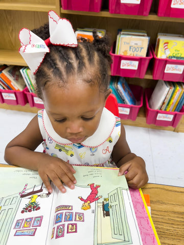 little girl at school reading a book wearing her Wee Ones back to school hair bow.