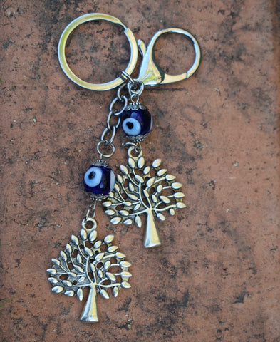 A key ring with blue evil eye beads and two leafy trees in silver