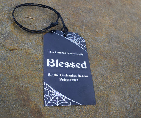 Tag saying this item has been officially blessed by the Beckoning Broom priestesses, resting on rock