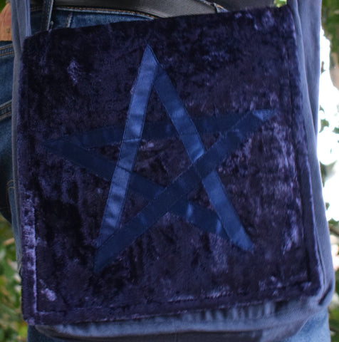 Person wearing a dark royal blue shoulder bag with a satin ribbon pentagram sewn on the front