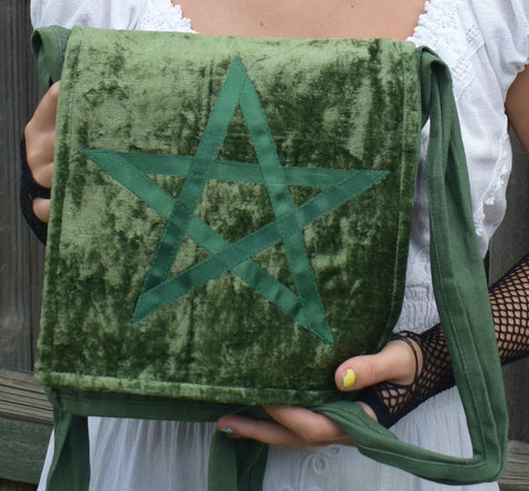 Person holding a green shoulder bag with a satin ribbon pentagram sewn on the front