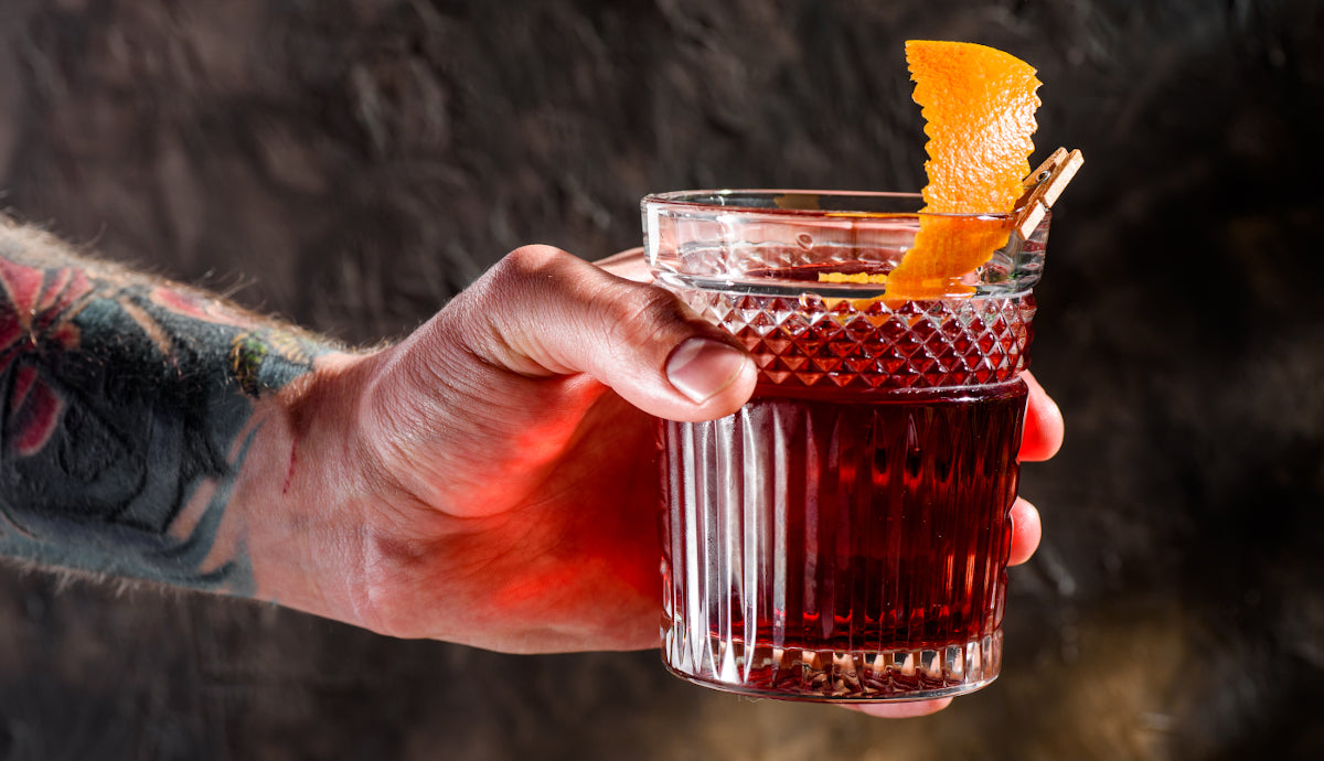 Tattooed bartender hands over the negroni