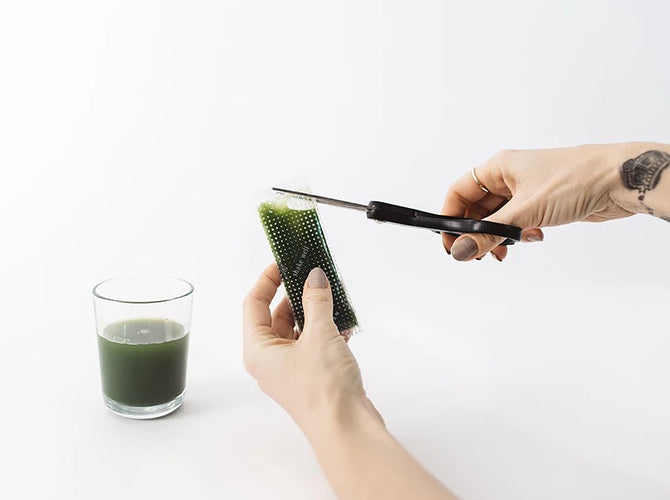 Wheatgrass juice package being cut with scissors