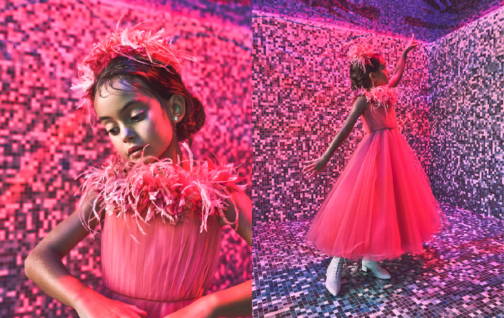 Silk princess dress in a coral pink sunset shade with handmade silk flower and ostrich feather trim