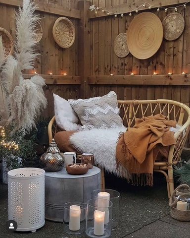 Bohemian inspired outdoor seating area with rattan sofa and mood lighting