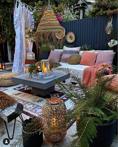 Bright and colourful outdoor seating area with a bohemian feel. Layering of textiles and wooden and rattan accessories.