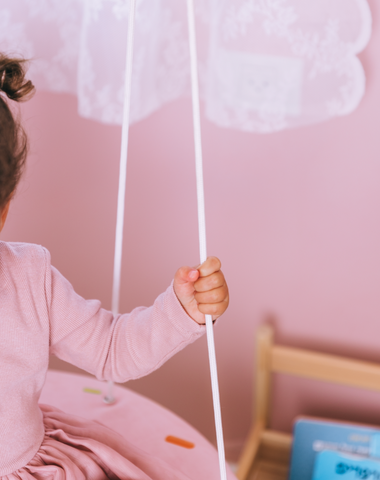 ילדה מחזיקה בחבלים של נדנדה מעוצבת בצורת דונאטס