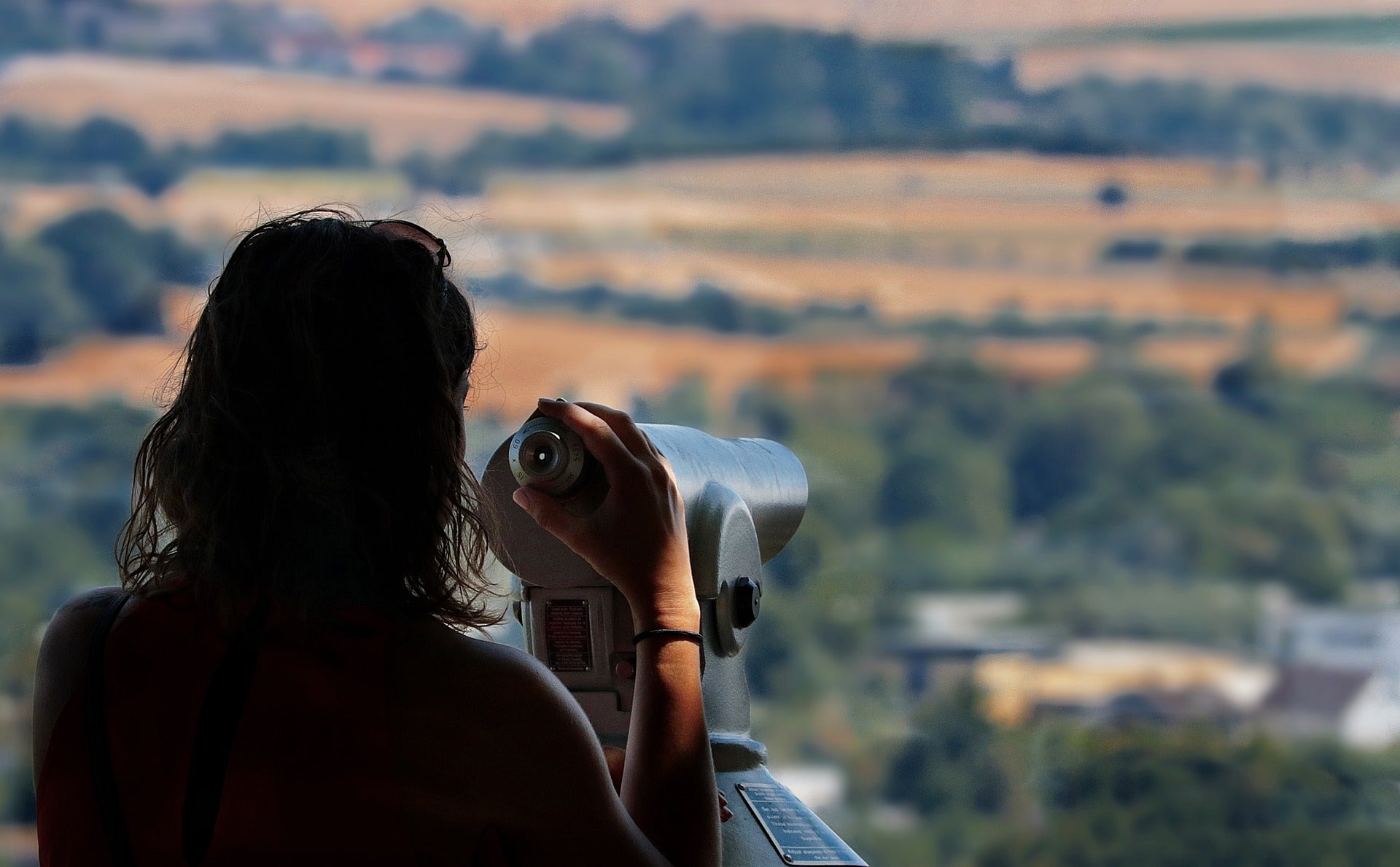 Frau guckt durch ein Fernglas in die Ferne