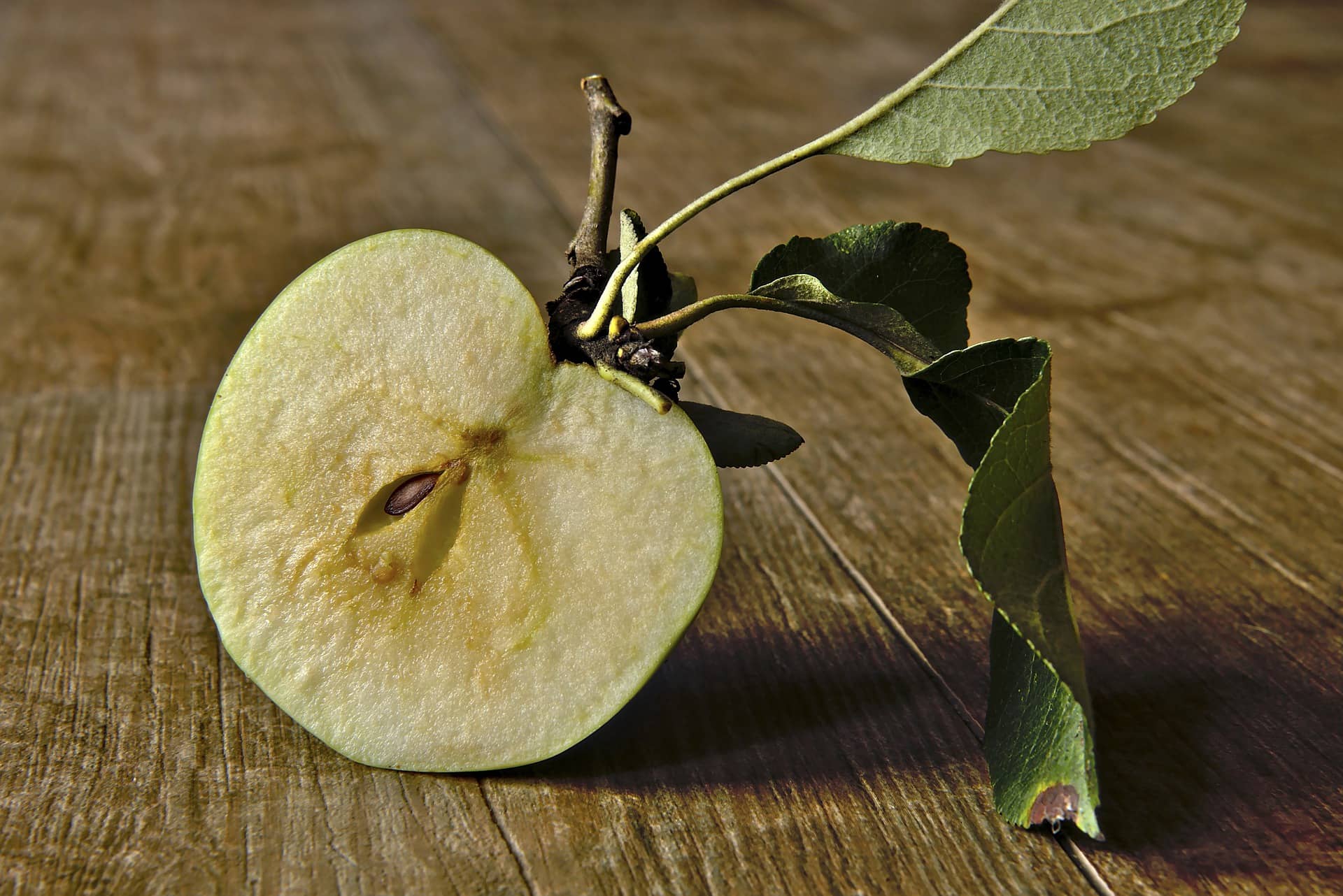 Ein halbierter grüner Apfel liebt auf einem Holztisch