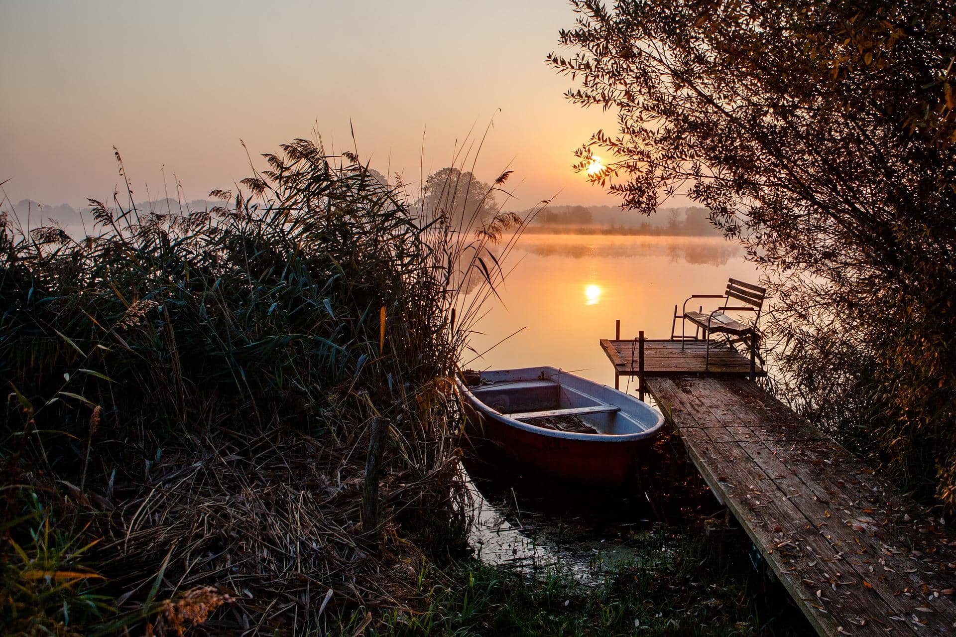 Sonnenuntergang an einem ruhigen See mit einem Steg und Boot