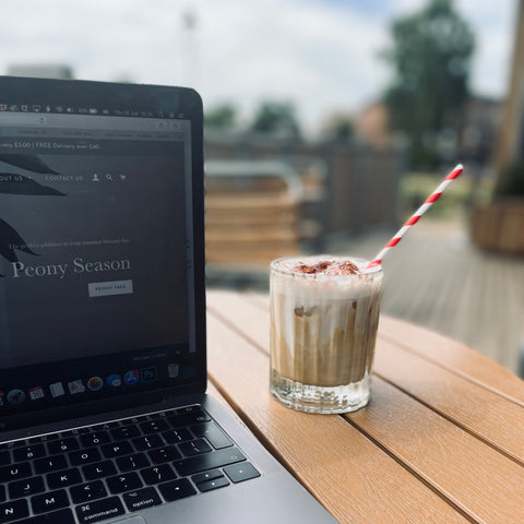 laptop open beside a glass of iced coffee