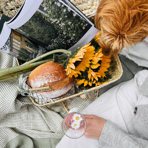 flat lay of a picnic set up with a basket holding sunflowers and a loaf of bread