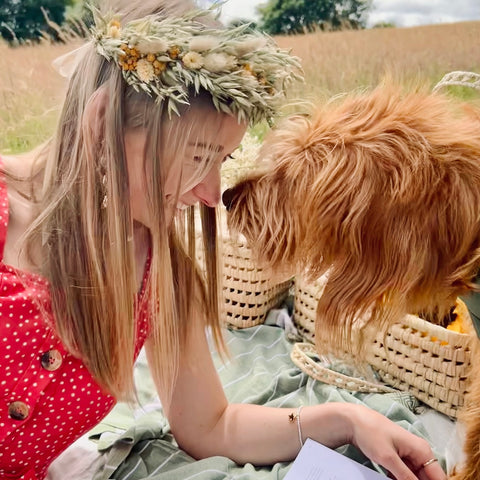 Woman wearing flower crown touching noses with a dog