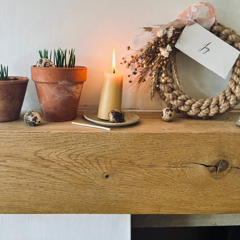 Mantle piece with a collection of plant pots, yellow candles and a Spring wreath