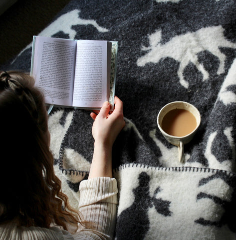 woman reading a book on a moose blanket