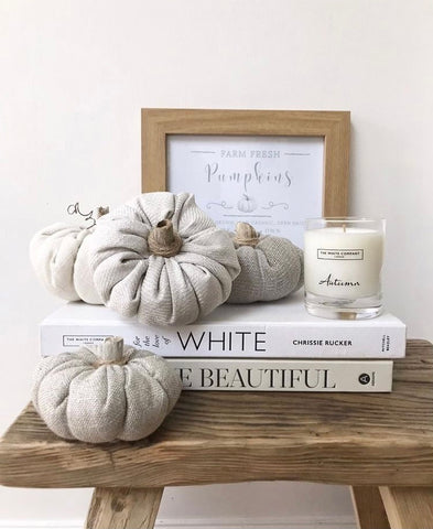 a wooden stool, with 2 stacked books, a candle and a skatter of fabric pumpkins