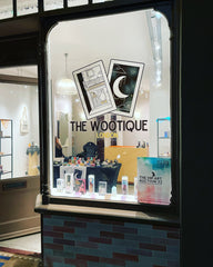 The wootique logo on a shop window with the lights on