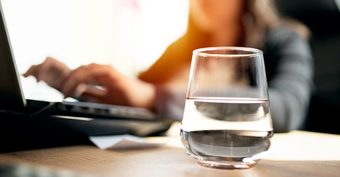 woman working with a glass of water on her desk