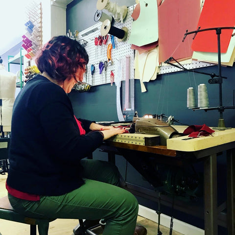 Ruby is shown in profile, sitting in her sewing studio, bent over her sewing machine.