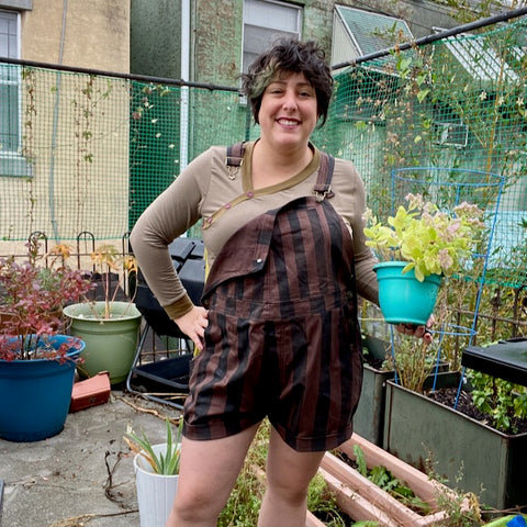 Ruby in handpainted self-made overalls holding a potted plant