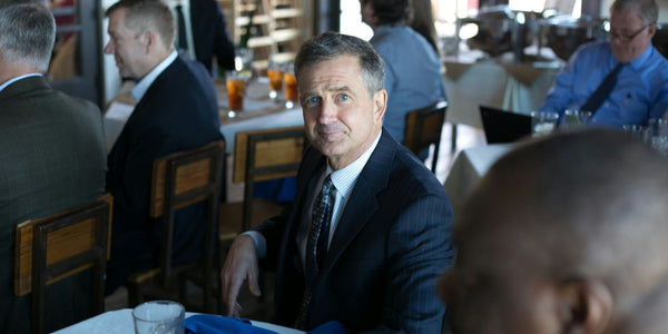 A professional man in a suit and tie sitting at a table, focused and ready for a meeting.