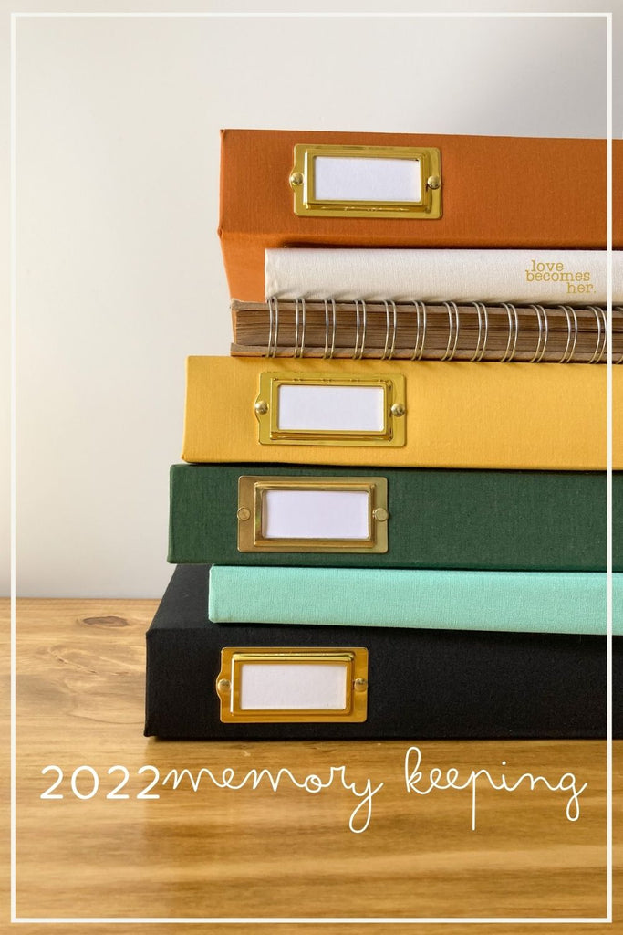 memory keeping in 2022 stack of albums and notebooks on wooden desktop