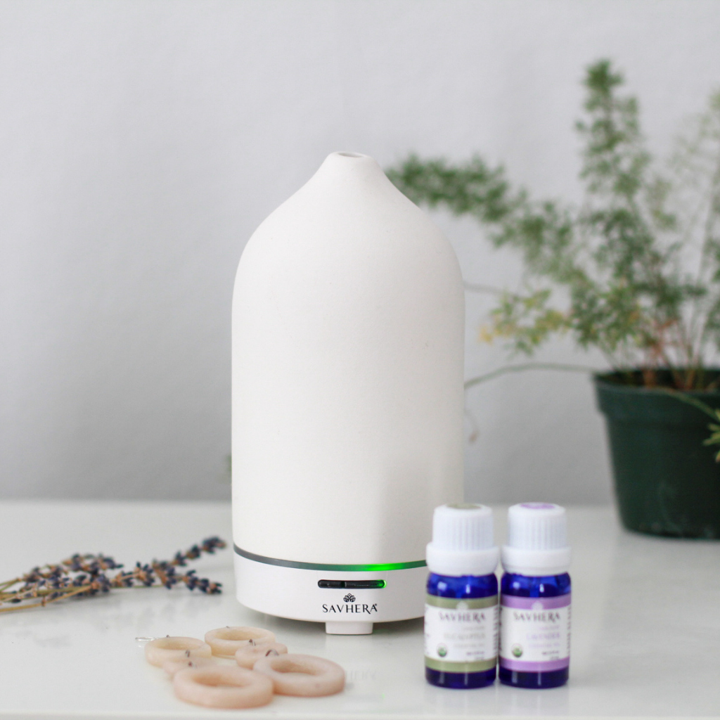lavender and eucalyptus essential oil in front of a diffuser with a pair of clay and silver diffusing earrings