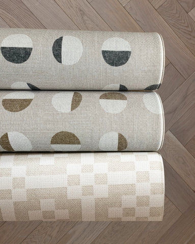 Three rolled baby crawling mats in neutral tones