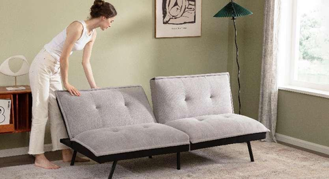 A woman is opening the backrest of a folding sofa ​