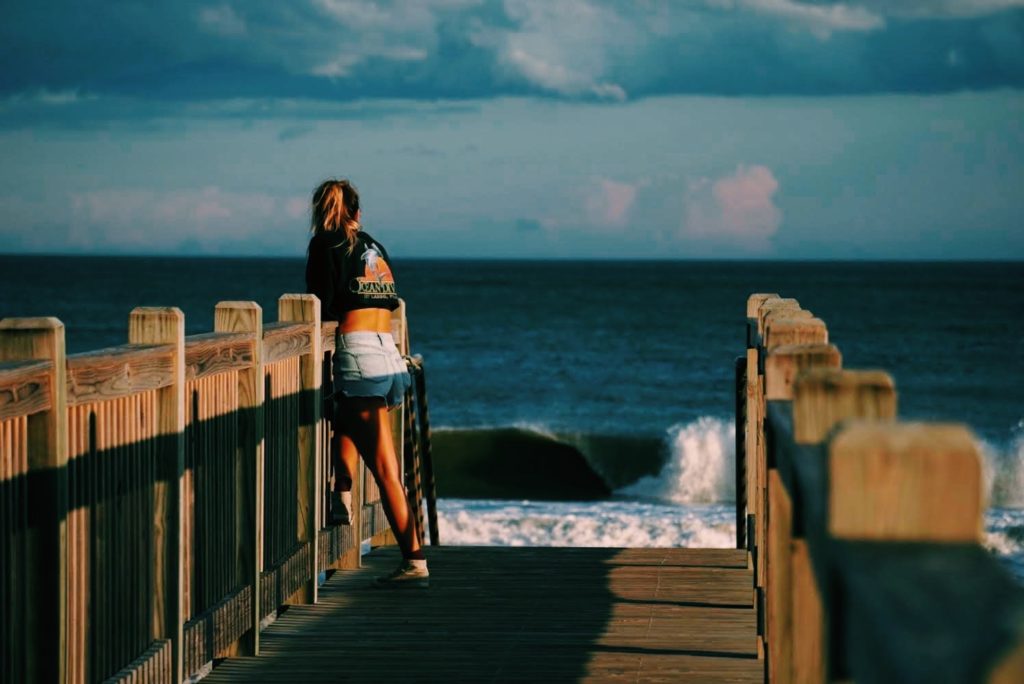 A girl on a East Coast board walk checking the surf.