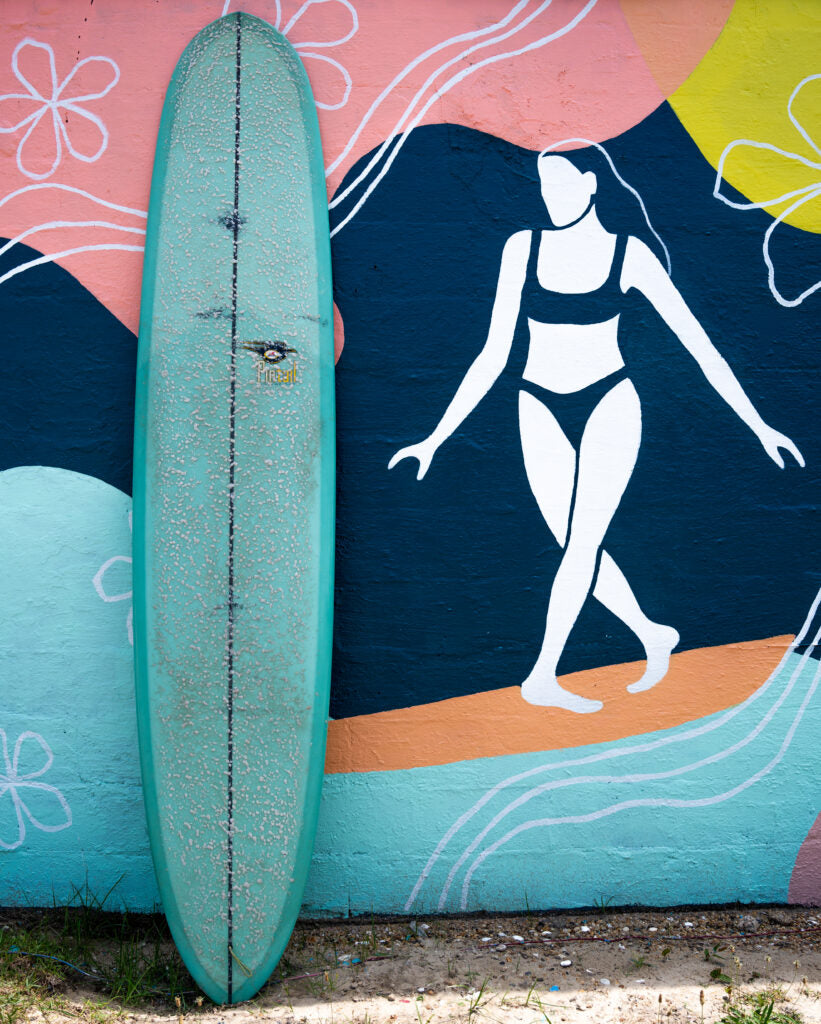 Bing Pintail Lightweight next to a mural of a woman surfing