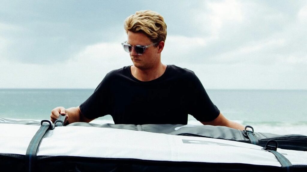 Surfer strapping down two surfboards on his vehicle roof using the FCS D Ring straps.