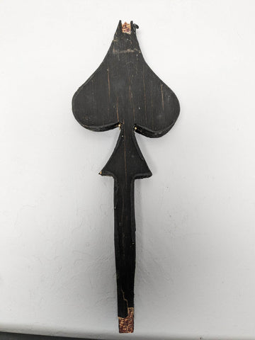 A wooden fineal in the shape of a spade from a pack of cards
