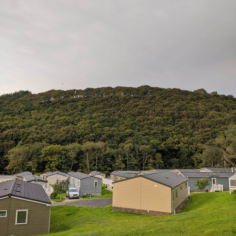 A holiday park with a wooded hill in the background.