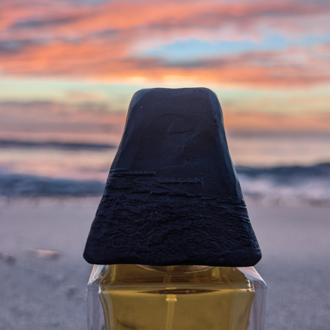 Close-up of the cap of British perfume Merge against a sunset. 