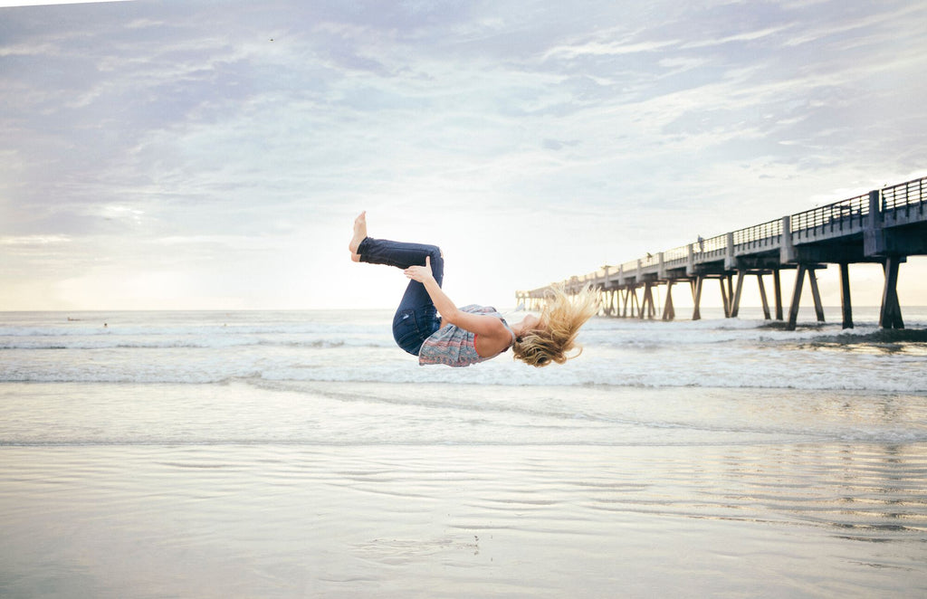 Femmes qui fait un saut périlleux sur la plage