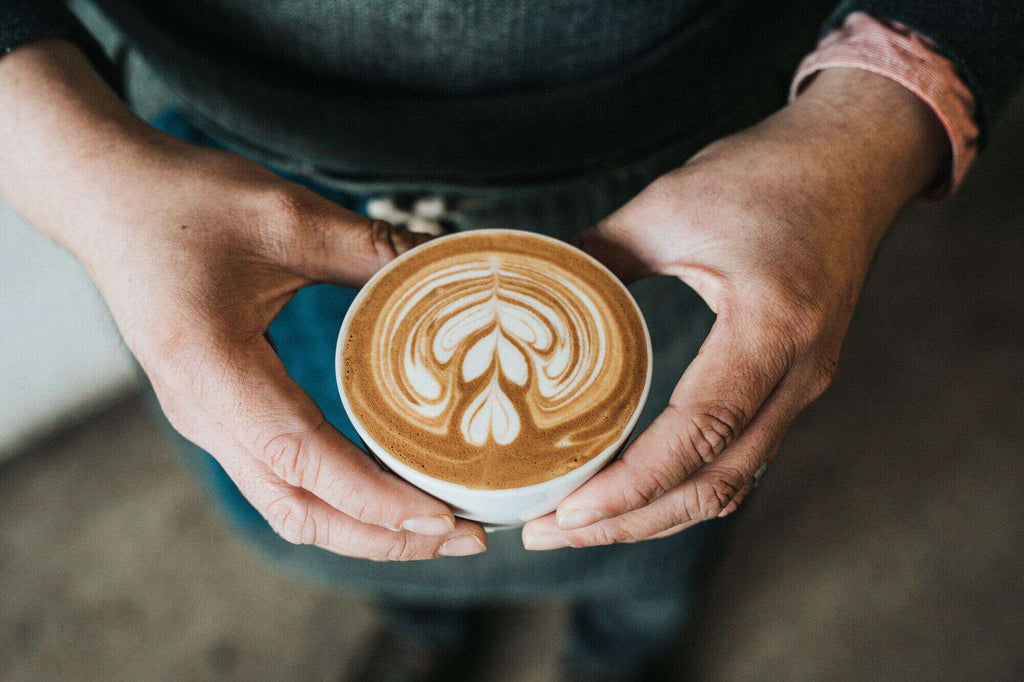 Homme tenant un capuccino entre ses deux mains