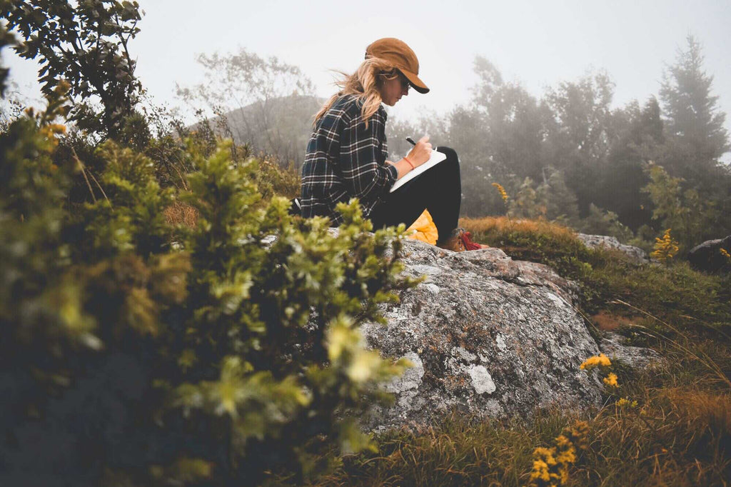 Femme qui tient son journal intime assise dans la nature