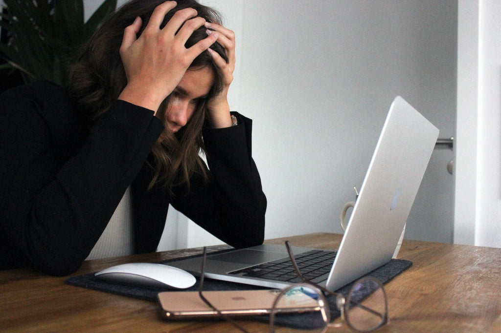 Une femme qui se tient la tete dans les mains au travail