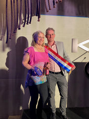 Jannene and Nick on a stage holding the Sydney Royal Beer and Cider show trophy and sash