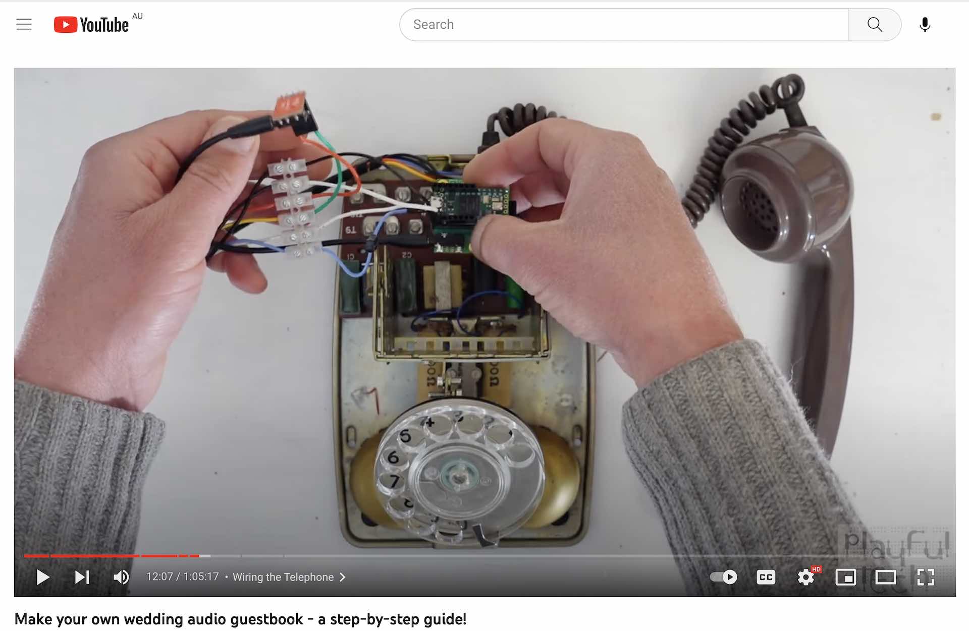 Close up of a vintage phone taken apart and two hands are adjusting the wiring inside