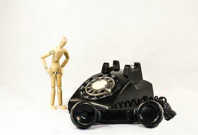 Vintage Black Telephone with handset on the ground. A posing figure stands over the top of it.