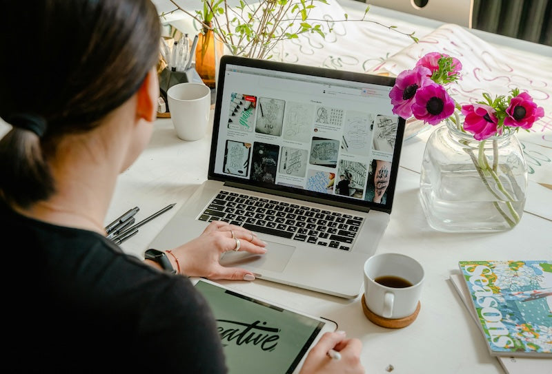 woman at macbook laptop looking at design images at her desk.