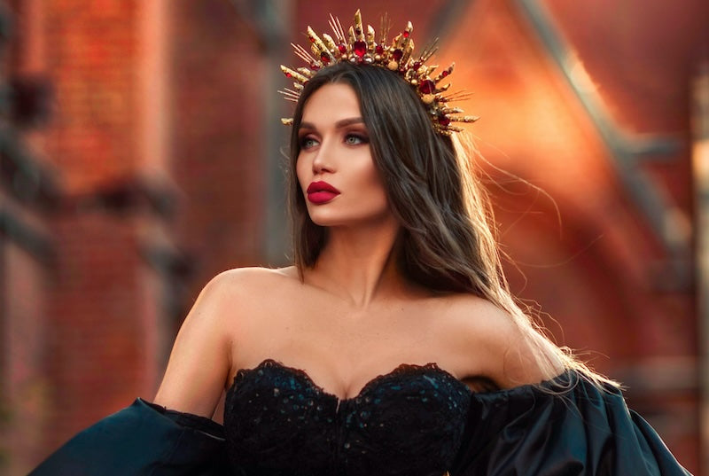 Woman in black gown wearing a star shaped crown on her head.