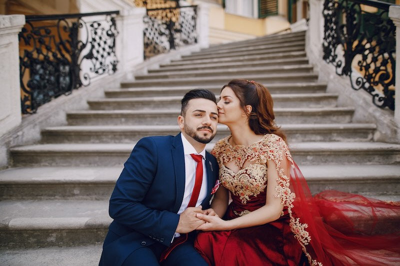 Beautiful formal couple sitting on elegant steps holding hands.