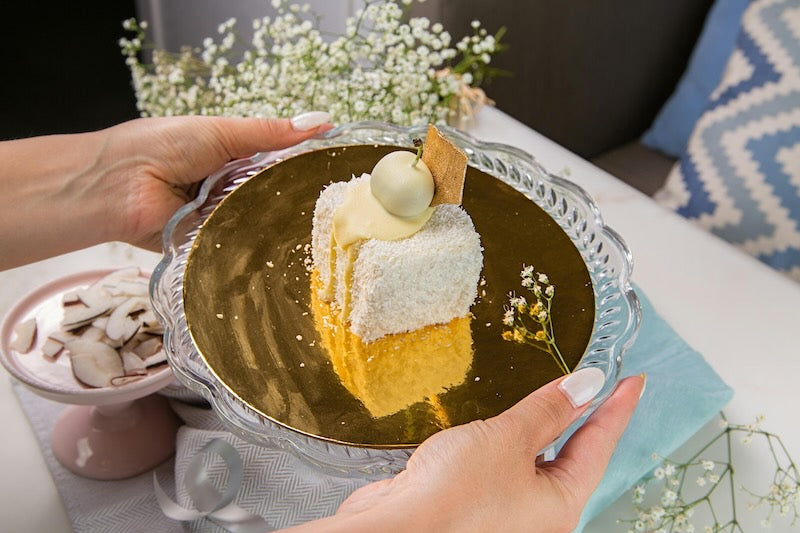 A decorative piece of gold and white cake on an ornate plate.