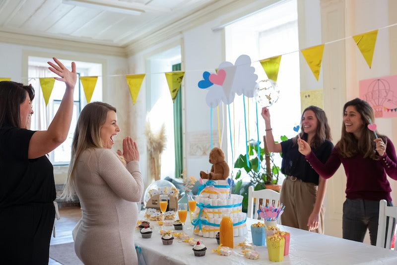 A party occurs indoors with people cheering a pregnant woman.