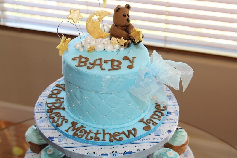 Blue baby shower cake with teddy bears on top.